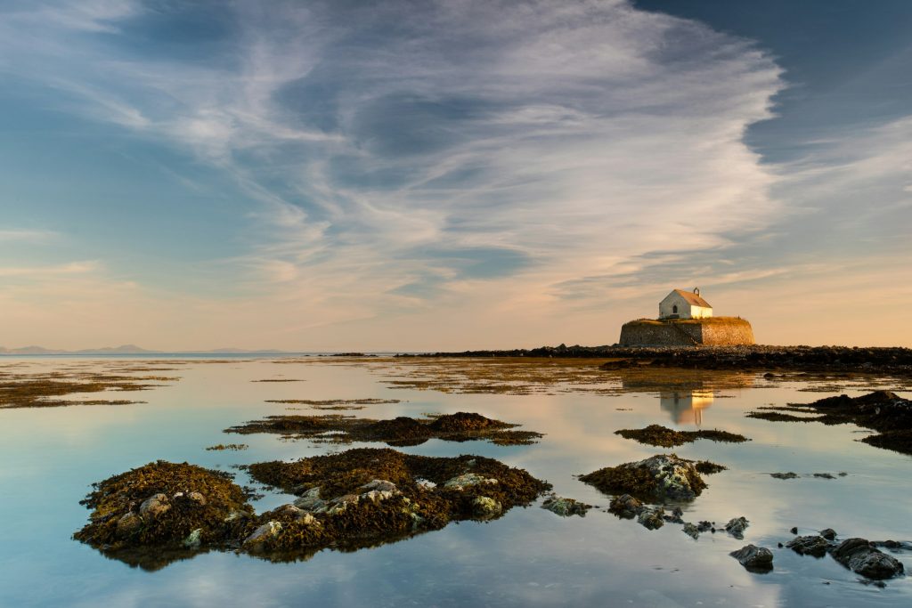 St Cwyfan’s church in the sea at low tide on Anglesey, with calm reflections